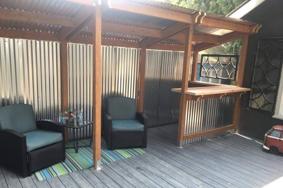 An outdoor covered seating area build with pressure-treated hem-fir posts and beams, with galvanized metal siding and roofing.