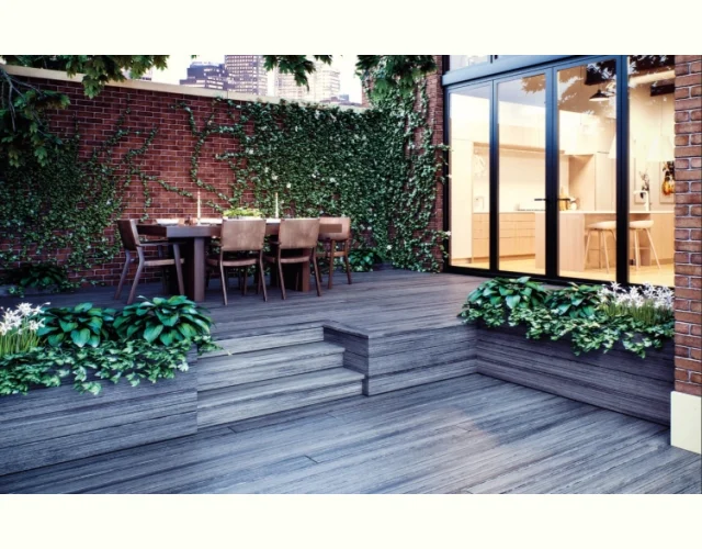 Deckorators Vista decking in Driftwood A multi-level deck built with Deckorators Vista decking in Driftwood with a table and chairs on the upper platform off of a wall of glass windows.